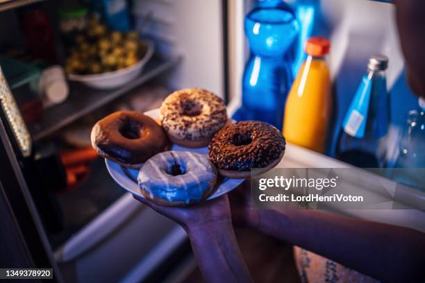 woman taking donuts out of the fridge - binge eating stock pictures, royalty-free photos & images