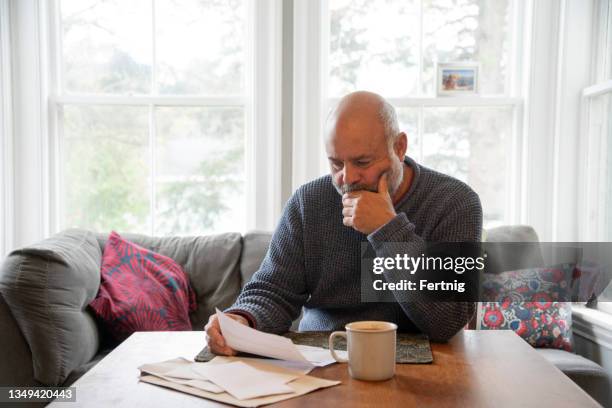 a mature man dealing with personal finances at home - stress test stockfoto's en -beelden