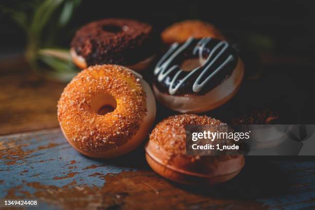 donut zum frühstück auf holzbrett - donuts stock-fotos und bilder