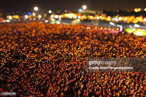 Thai people hold up a candles and sing a song honouring King Bhumibol Adulyadej during a ceremony celebrating the King's birthday at Royal Ground on...