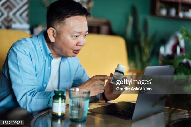 senior asian man having a virtual appointment with doctor online, consulting his prescription and choice of medication on laptop at home. telemedicine, elderly and healthcare concept - diabetes pills stock pictures, royalty-free photos & images