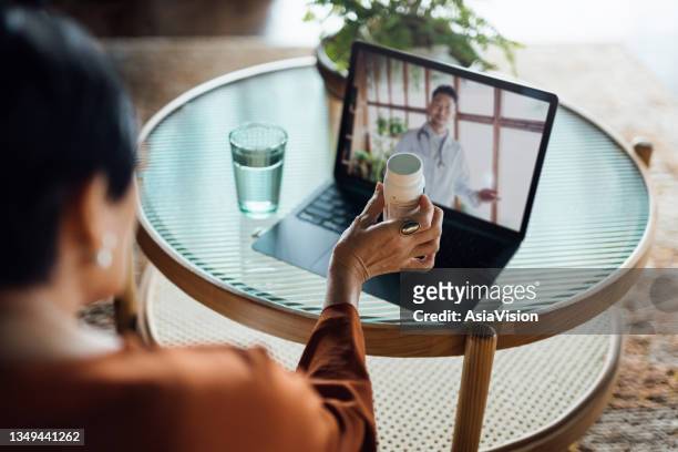 senior asian woman having a virtual appointment with doctor online, consulting her prescription and choice of medication on laptop at home. telemedicine, elderly and healthcare concept - diabetes pills stock pictures, royalty-free photos & images