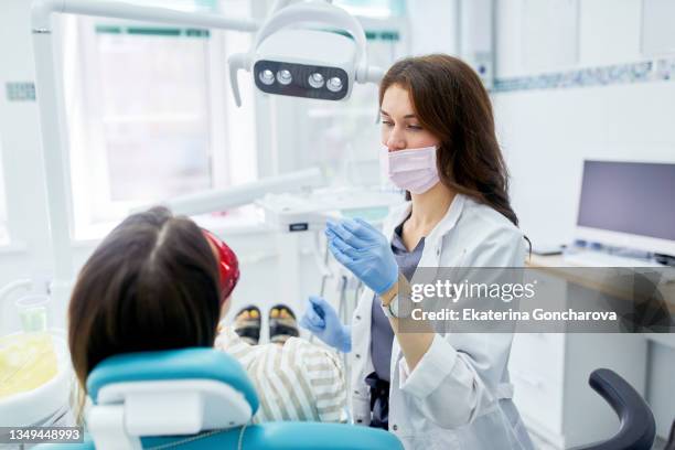 a young female dentist treats the teeth of a patient in a dental chair. - dental office - fotografias e filmes do acervo