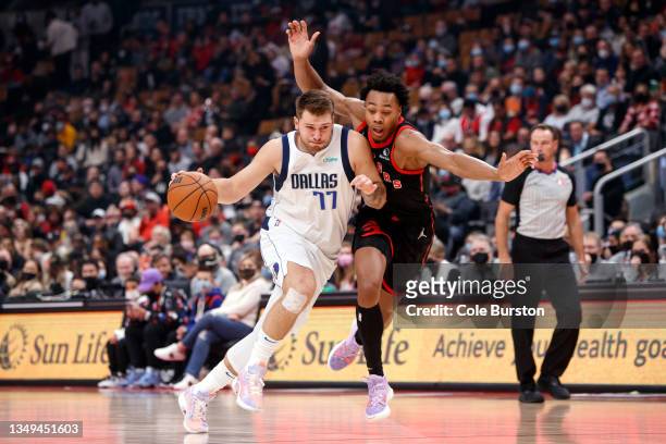 Luka Doncic of the Dallas Mavericks drives on Scottie Barnes of the Toronto Raptors during their NBA game at Scotiabank Arena on October 23, 2021 in...