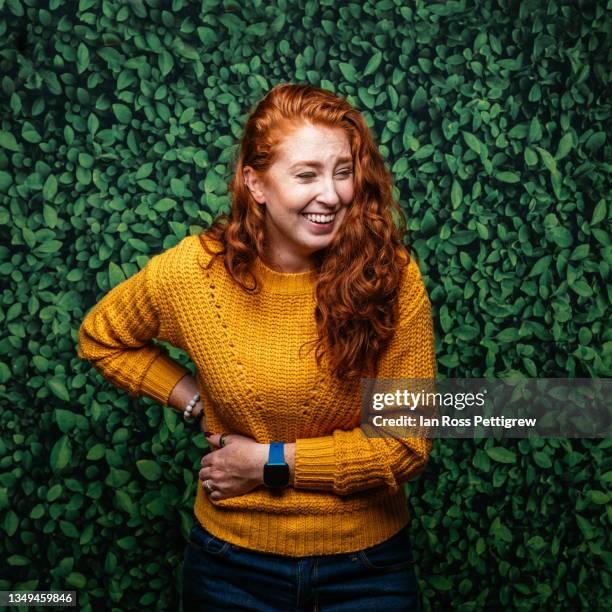 cute redhead woman, on green leaf background with yellow sweater - woman on plain background stock pictures, royalty-free photos & images