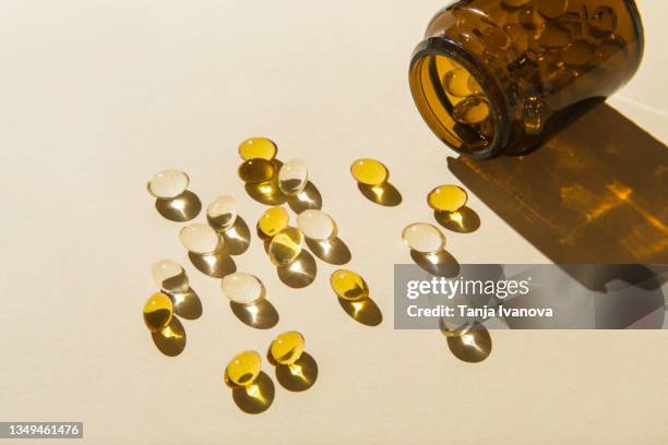 vitamin d capsules poured out of the bottle on a beige background. - ビタミンd ストックフォトと画像