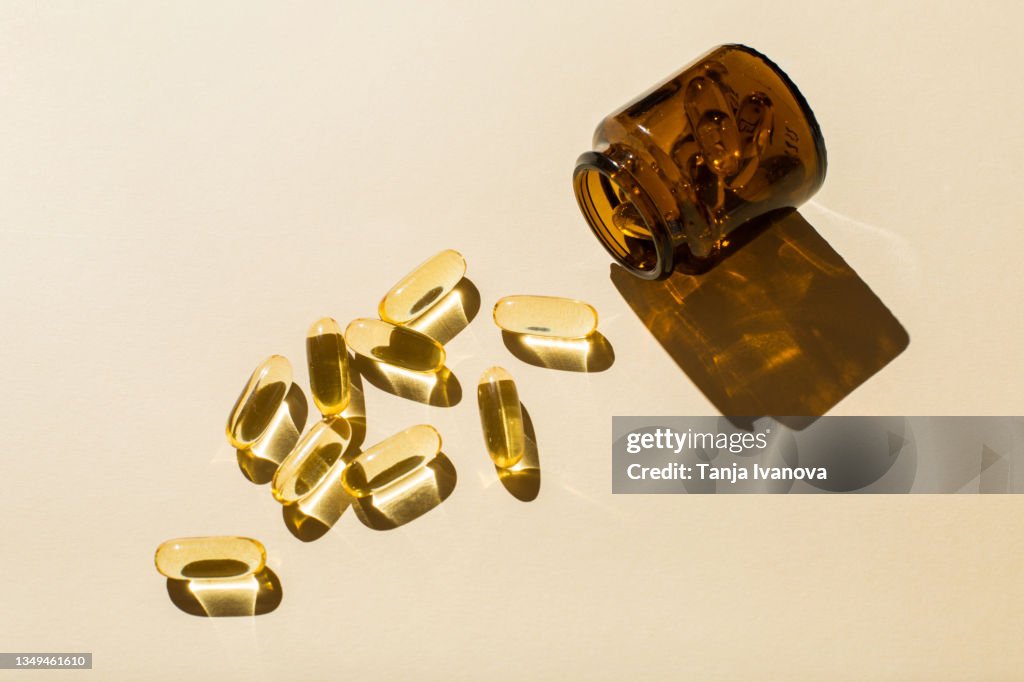 Omega 3 fish oil capsules and a glass bottle on a beige background.