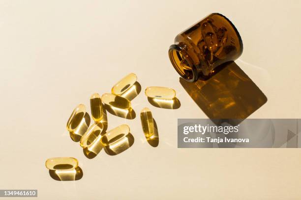 omega 3 fish oil capsules and a glass bottle on a beige background. - vitamine a stockfoto's en -beelden