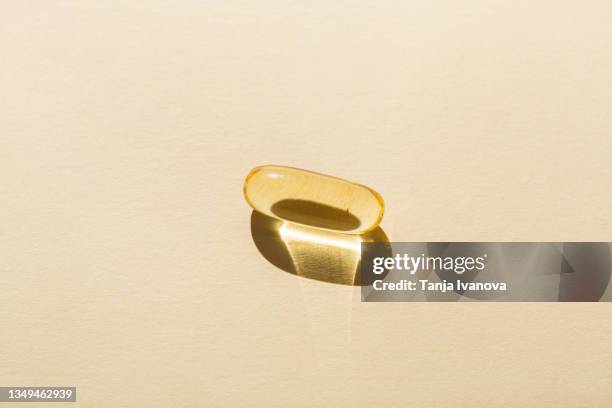 soft capsule of fish oil with omega 3 on a beige background. - fish oil foto e immagini stock