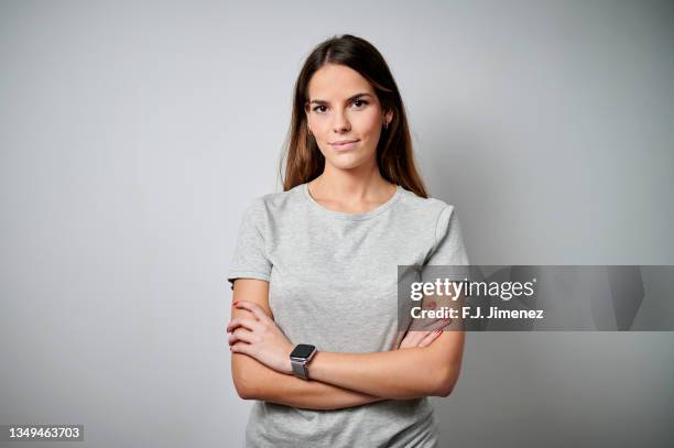 portrait of woman wearing t-shirt with plain background - arms crossed fotografías e imágenes de stock