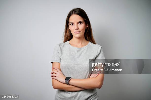 portrait of woman wearing t-shirt with plain background - folded arms stockfoto's en -beelden