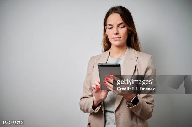portrait of businesswoman using tablet in simple background - chaqueta de ante fotografías e imágenes de stock