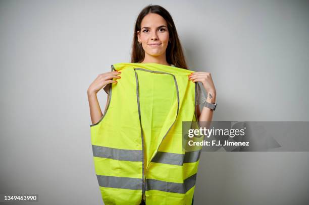 woman holding safety vest on white background - waistcoat stock-fotos und bilder