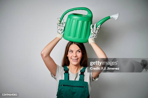 woman gardener carrying a watering can on her head - grüner handschuh stock-fotos und bilder