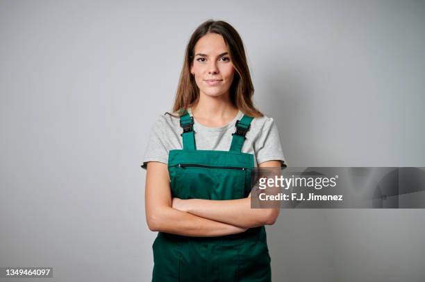 portrait of woman in overalls on white background - manual worker stockfoto's en -beelden