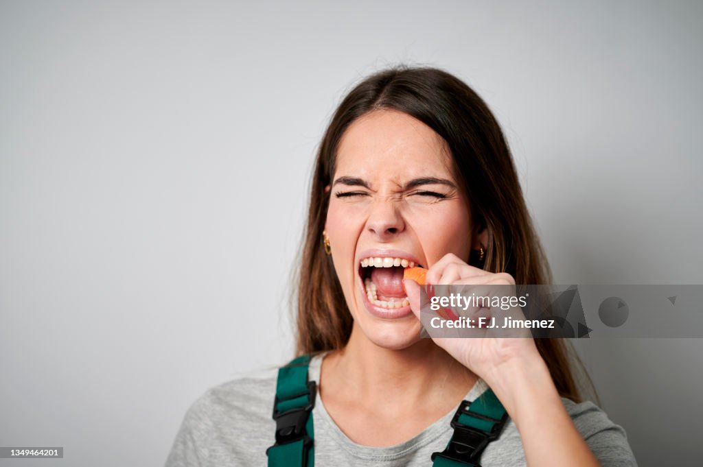 Close-up of woman biting a carrot