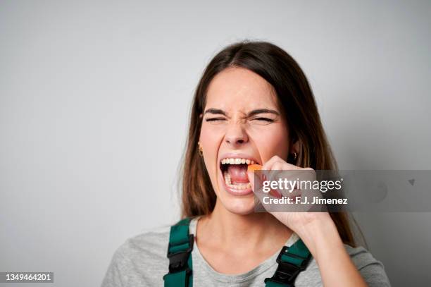 close-up of woman biting a carrot - tough lady stockfoto's en -beelden