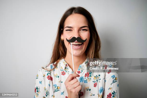 portrait of smiling woman with fake mustache on plain background - moustache isolated stock pictures, royalty-free photos & images