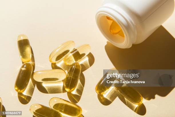 omega 3 fish oil capsules and a bottle on a beige background. - vitamin a stock pictures, royalty-free photos & images