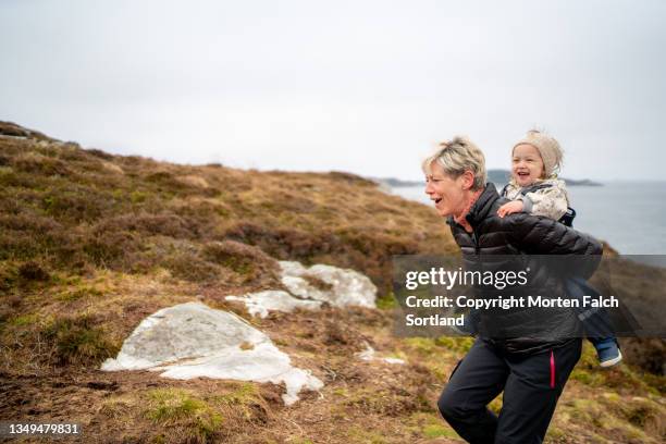 grandmother giving her grandchild a piggyback ride - family hiking in spring outdoors foto e immagini stock