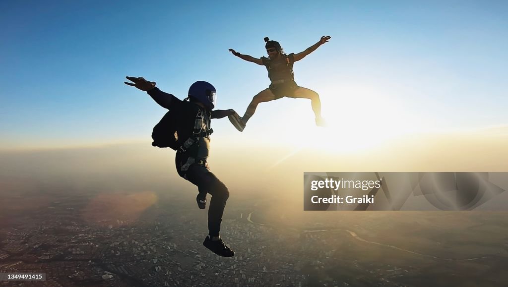 Skydivers holding hands at the sunset