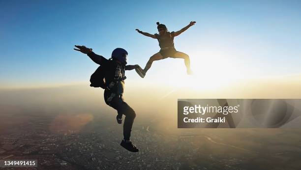 skydivers holding hands at the sunset - paracadutista foto e immagini stock