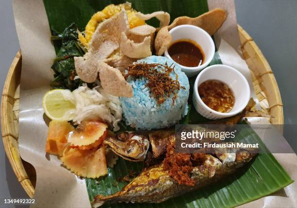 nasi kerabu or known as blue rice served with fried fish, salad and fish crackers - traditional malay food stock pictures, royalty-free photos & images