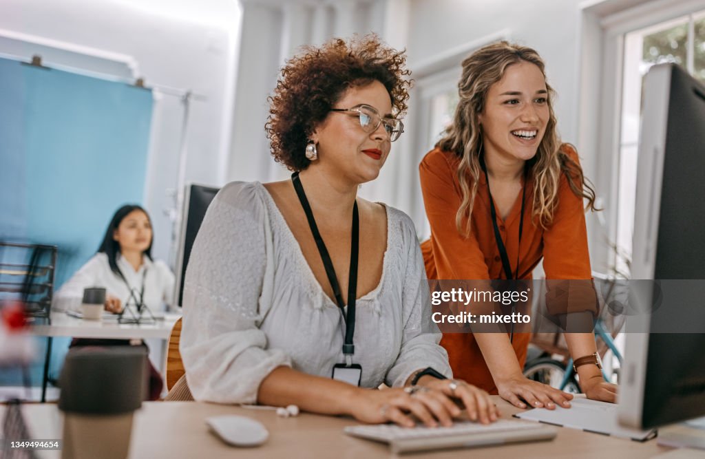 Due colleghi di lavoro che lavorano insieme su un computer desktop in ufficio