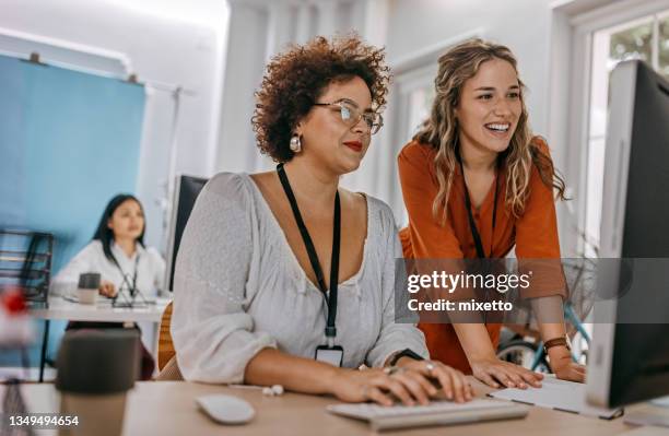 two business colleagues working together on desktop computer at office - coworker stock pictures, royalty-free photos & images