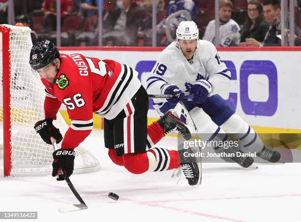 Erik Gustafsson of the Chicago Blackhawks looses his balance trying to control the puck under pressure from Jason Spezza of the Toronto Maple Leafs...