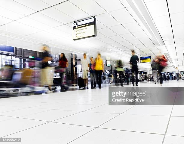 crowd walks towards camera in an airport concourse - now voyager stock pictures, royalty-free photos & images