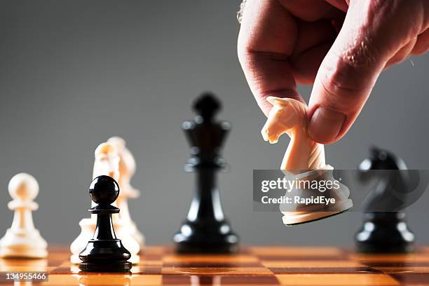 mano del hombre se mueve blanco caballo en posición sobre chessboard - (position) fotografías e imágenes de stock