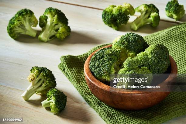 fresh raw broccoli in bowl on rustic table. - brocoli stock-fotos und bilder