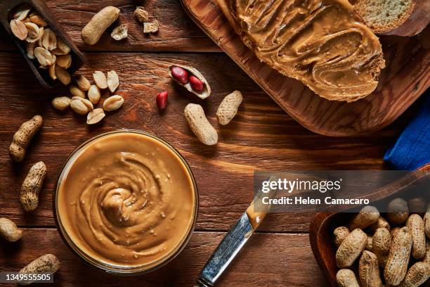 peanut butter scattered on a slice of bread on rustic background - pindakaas stockfoto's en -beelden