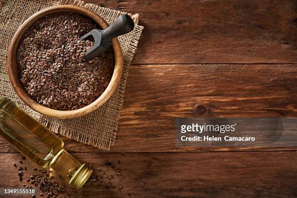 top view of flax seeds in a bowl and linseed oil on wooden backdrop. flaxseed dietary fiber - cereales stock pictures, royalty-free photos & images