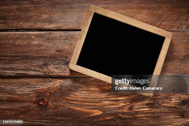 empty blackboard with wooden frame on rustic wooden table - ardósia quadro imagens e fotografias de stock