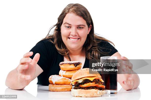 plump young lady about to grab pile of junk food - fat people eating donuts stock pictures, royalty-free photos & images