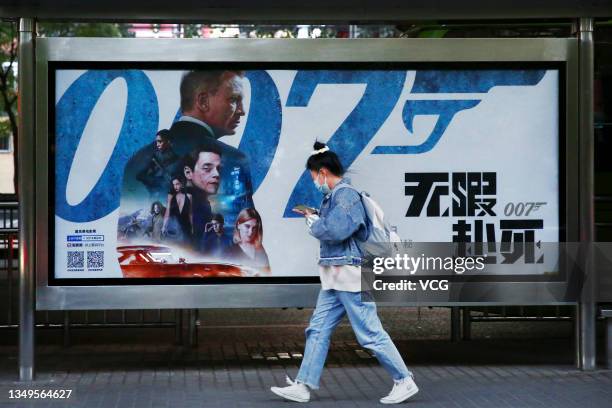 Pedestrian walks by a billboard for film 'No Time to Die' at a bus station on October 27, 2021 in Beijing, China.