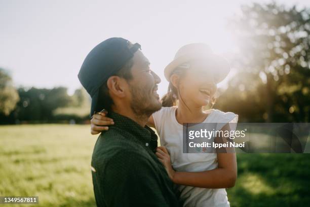 father and young daughter hugging in park at sunset, tokyo - 子供　日本人　笑顔 ストックフォトと画像