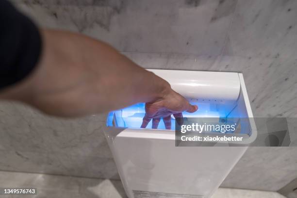 use a hand dryer to dry a person's hands - hand dryer stock pictures, royalty-free photos & images