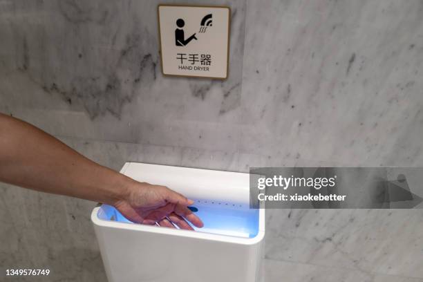 high angle view of using a hand dryer to dry a person's hands - hand dryer stock pictures, royalty-free photos & images