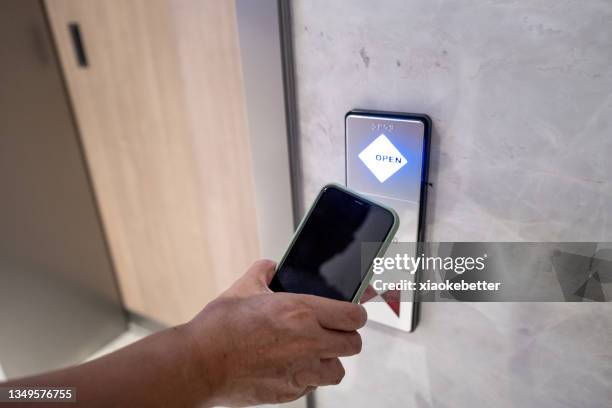 human hand holding a mobile phone to open the automatic induction lock of the door - sensor stock pictures, royalty-free photos & images