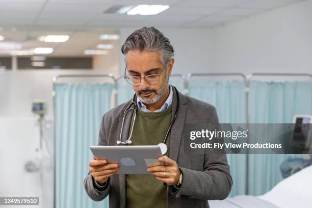 doctor reviewing patient medical record on digital tablet - medisch dossier stockfoto's en -beelden