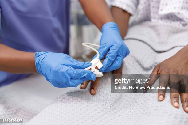 nurse using pulse oximeter on hospitalized patient - intensieve zorg stockfoto's en -beelden