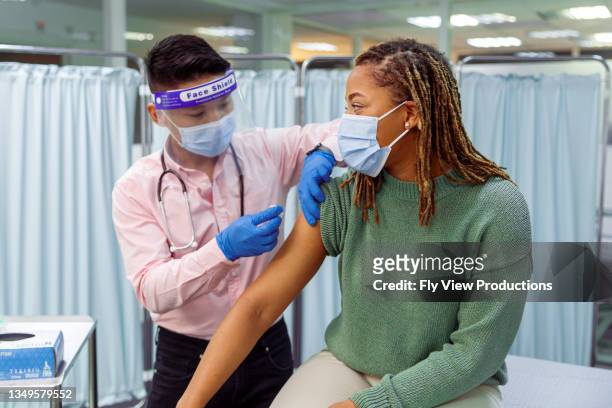 black woman receiving covid-19 vaccination injection - covid 19 vaccine stock pictures, royalty-free photos & images