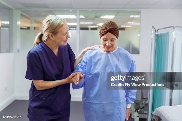 nurse assisting female cancer patient walk through hospital ward - cancer support stock pictures, royalty-free photos & images