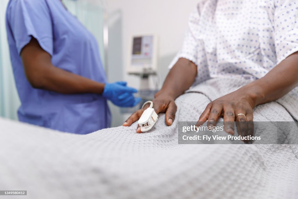 Infirmière utilisant un oxymètre de pouls sur un patient hospitalisé