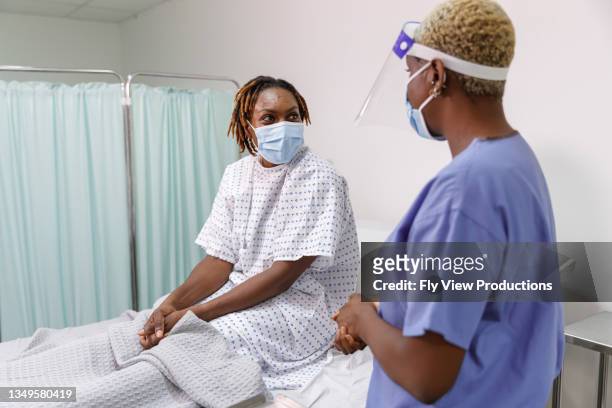 krankenschwester kümmert sich um patienten mit covid-19 im krankenhaus - african mask stock-fotos und bilder