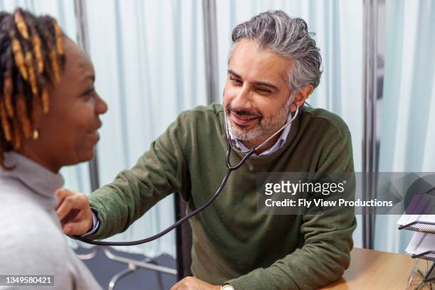 doctor checking woman's heartbeat at medical appointment - auscultation woman stock pictures, royalty-free photos & images