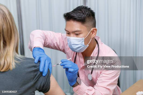 male nurse giving patient covid-19 vaccination shot - covid vaccination stock pictures, royalty-free photos & images